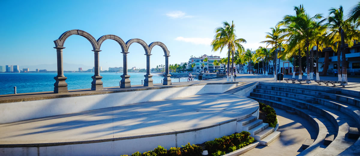 Los arcos icónicos del Malecón de Puerto Vallarta, enmarcados por el océano y la vibrante vida urbana.