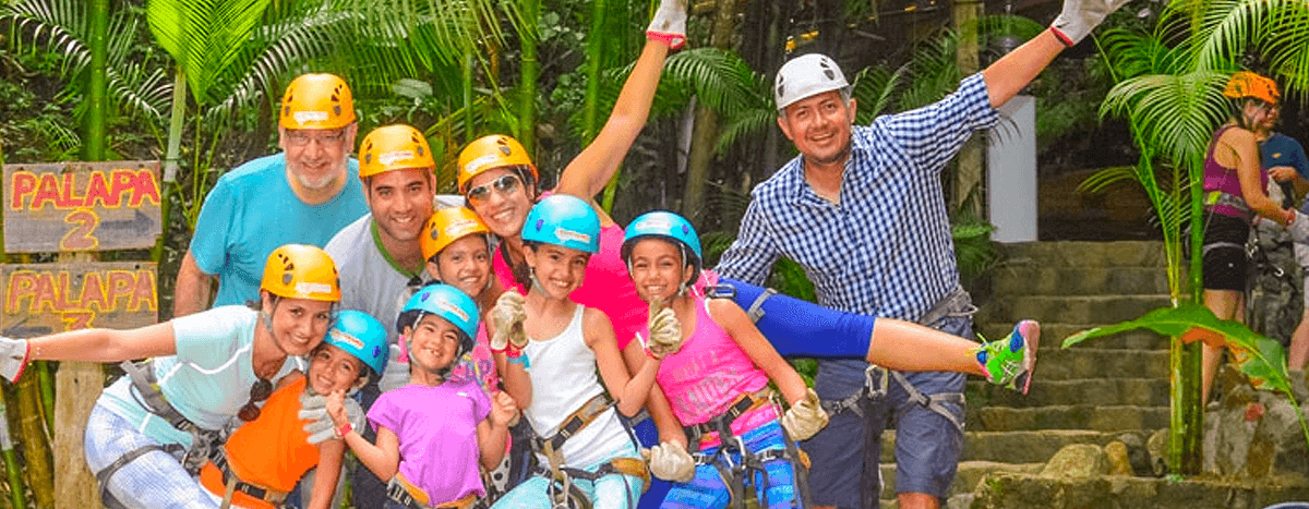 Familia disfrutando de una emocionante aventura en tirolesa en Puerto Vallarta, surcando el dosel de la selva.