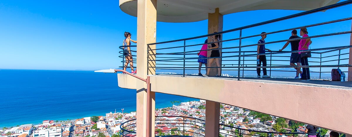 Personas disfrutando de vistas impresionantes de Puerto Vallarta y la Bahía de Banderas desde el Mirador de la Cruz.